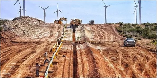 KES crew laying pipeline with wind turbines in the background
