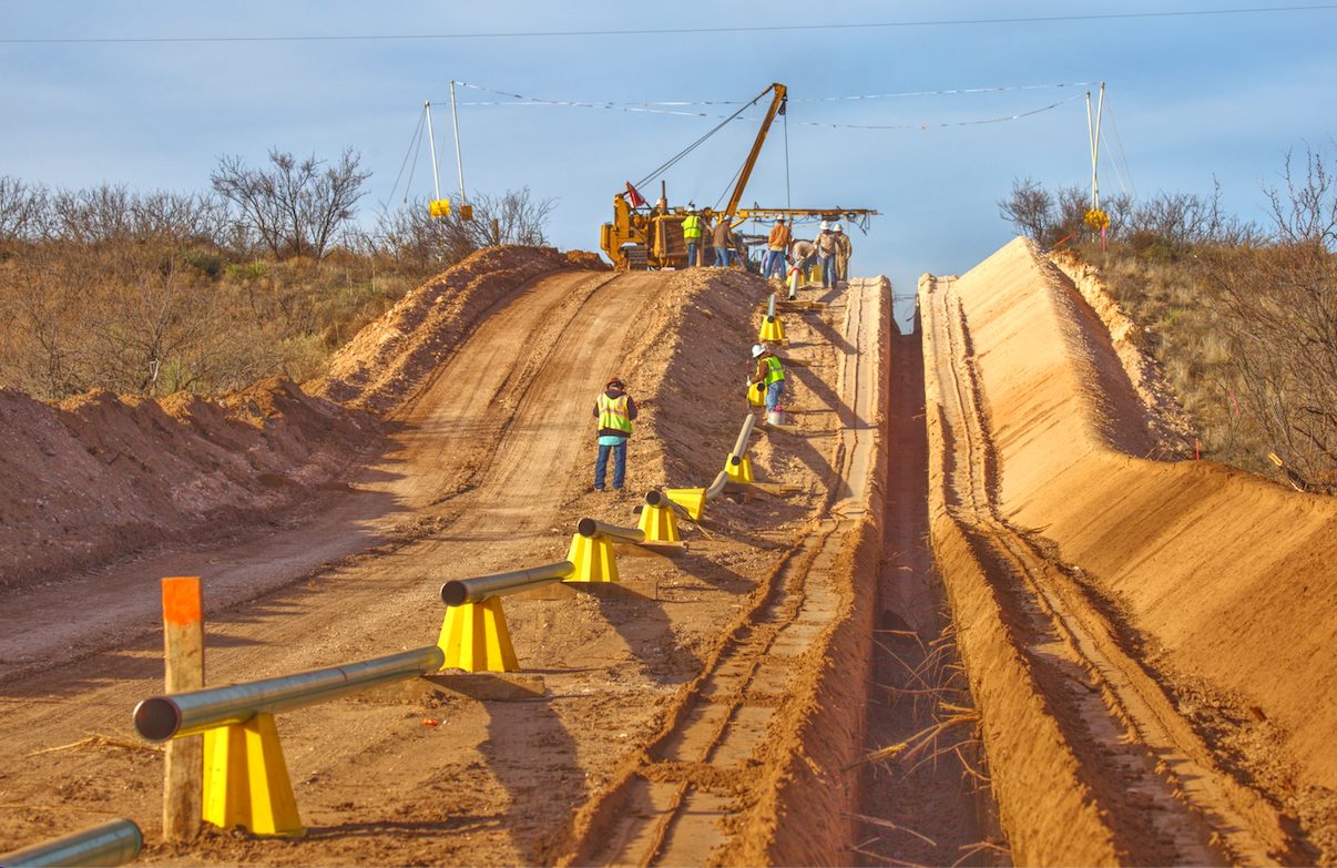 Crew using a sideboom to lower pipe into the trench during an integrity dig