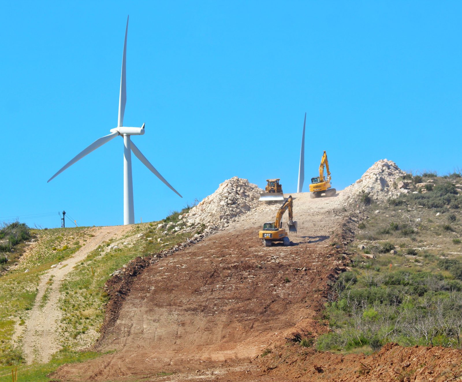 Dozers and excavators clearing and grading a hillside well pad site